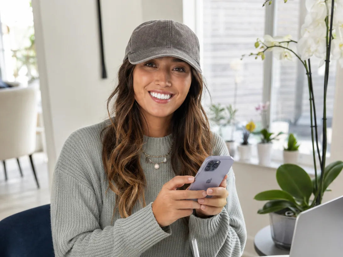 A customer smiling at her phone at a table with a laptop and coffee